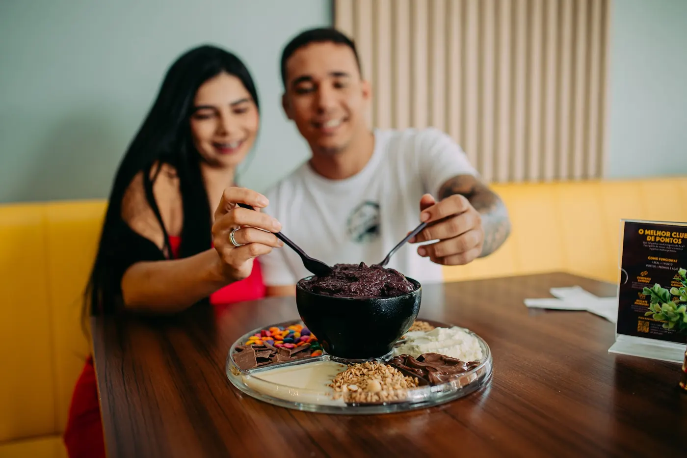 Casal dividindo uma tigela de açaí em uma loja Açaíst